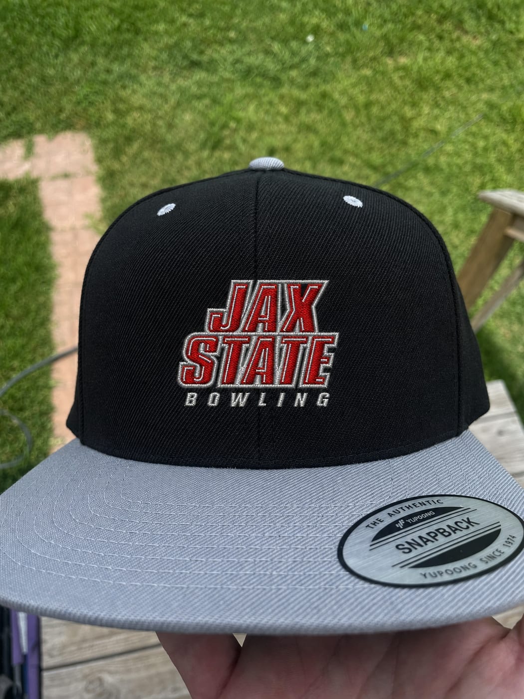 Black snapback with a grey brim embroidered with Jax State Bowling in red lettering outlined in white